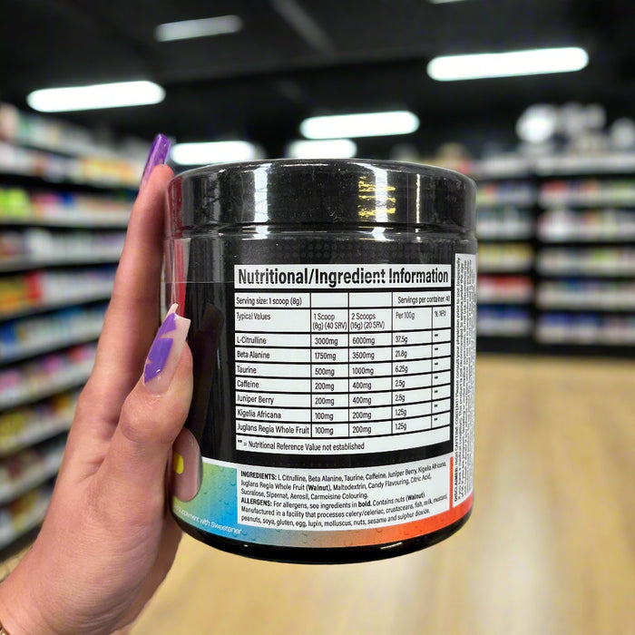 Close-up of (Trained By JP DNFM New Pre Workout 320g) held up inside My Supplement Shop, clearly showing Nutritional Values on the packaging in a Sports NutritionĀ setting.