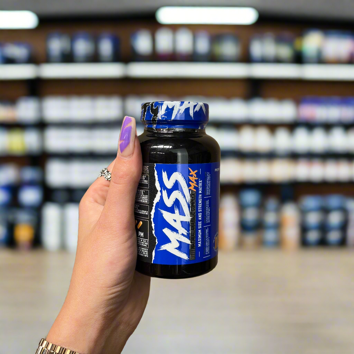 Close-up of Performax Labs MassMax 120 Capsules) held up inside My Supplement Shop, clearly showing the front label in a Sports Nutrition setting.
